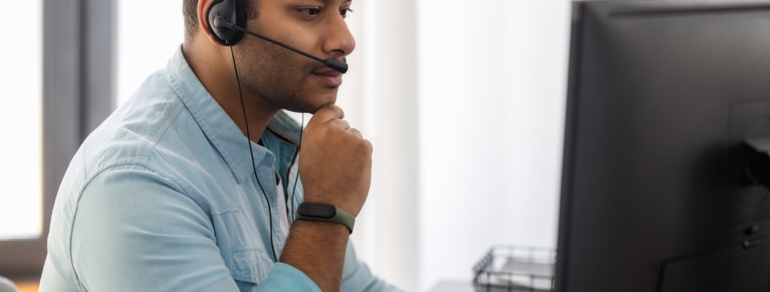 Concentrated man call center worker in headphones is working at modern office. Portrait of Asian male support employee